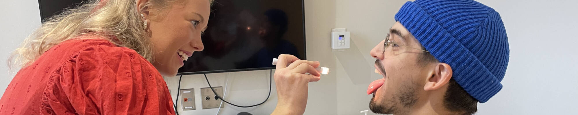 A faculty member examines the inside of a student's mouth with a flashlight